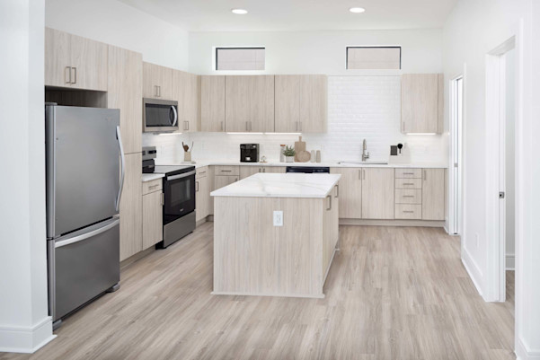 Townhome kitchen with light wood cabinets, white quartz countertops, stainless steel appliances, and white subway tile backsplash at Camden Belmont apartments in Dallas, TX
