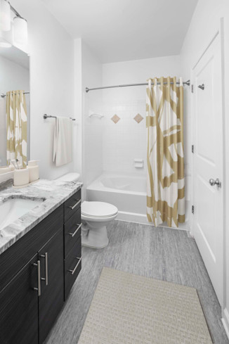 Bathroom with granite countertops and bathtub with curved shower rod at Camden Dulles Station apartments in Herndon, VA