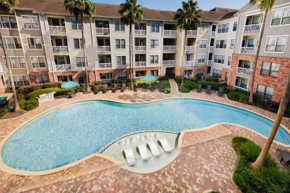 Resort style swimming pool daytime palm trees at Camden Heights Apartments in Houston, TX