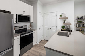 Renovated kitchen with white cabinets and beige grey quartz countertops at Camden Shadow Brook apartments in Austin, TX