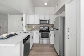 Luxurious kitchen with stainless steel appliances, white quartz countertops, subway tile backsplash, and space for barstool seating