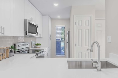 Modern kitchen with white quartz countertops, gray subway tile backsplash, and stainless steel appliances