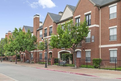 Building exterior showing sidewalk with benches and trees