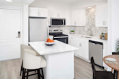 White contemporary kitchen with white quartz countertops and herringbone backsplash at Camden Grandview in Charlotte, NC