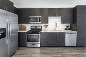 Modern kitchen with stainless steel appliances, white quartz countertops with subway tile backsplash, and wood-like flooring