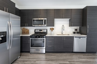 Modern kitchen with stainless steel appliances, white quartz countertops with subway tile backsplash, and wood-like flooring