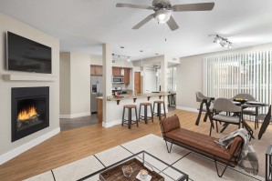 Open concept living room with fireplace and dining room near kitchen island with barstool seating 