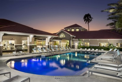 Resort style swimming pool at night alongside 24 hour fitness center