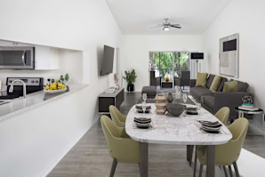 Living and dining room with sliding glass doors to patio, wood-look flooring, and ceiling fan at Camden Portofino apartments in Pembroke Pines, FL