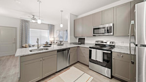 First-floor kitchen and living room with wood-style flooring and taupe cabinets at Camden Leander apartments in Leander, Tx