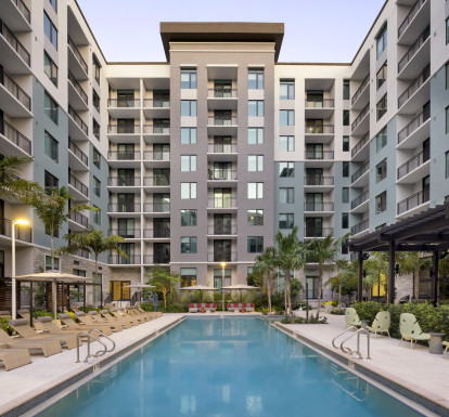 Pool with sundeck and cabanas surrounded by lush landscaping at Camden Atlantic in Plantation, Florida.