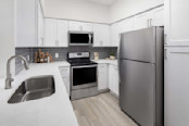 Kitchen with white quartz countertops and white shaker cabinets at Camden Addison apartments in Addison, TX