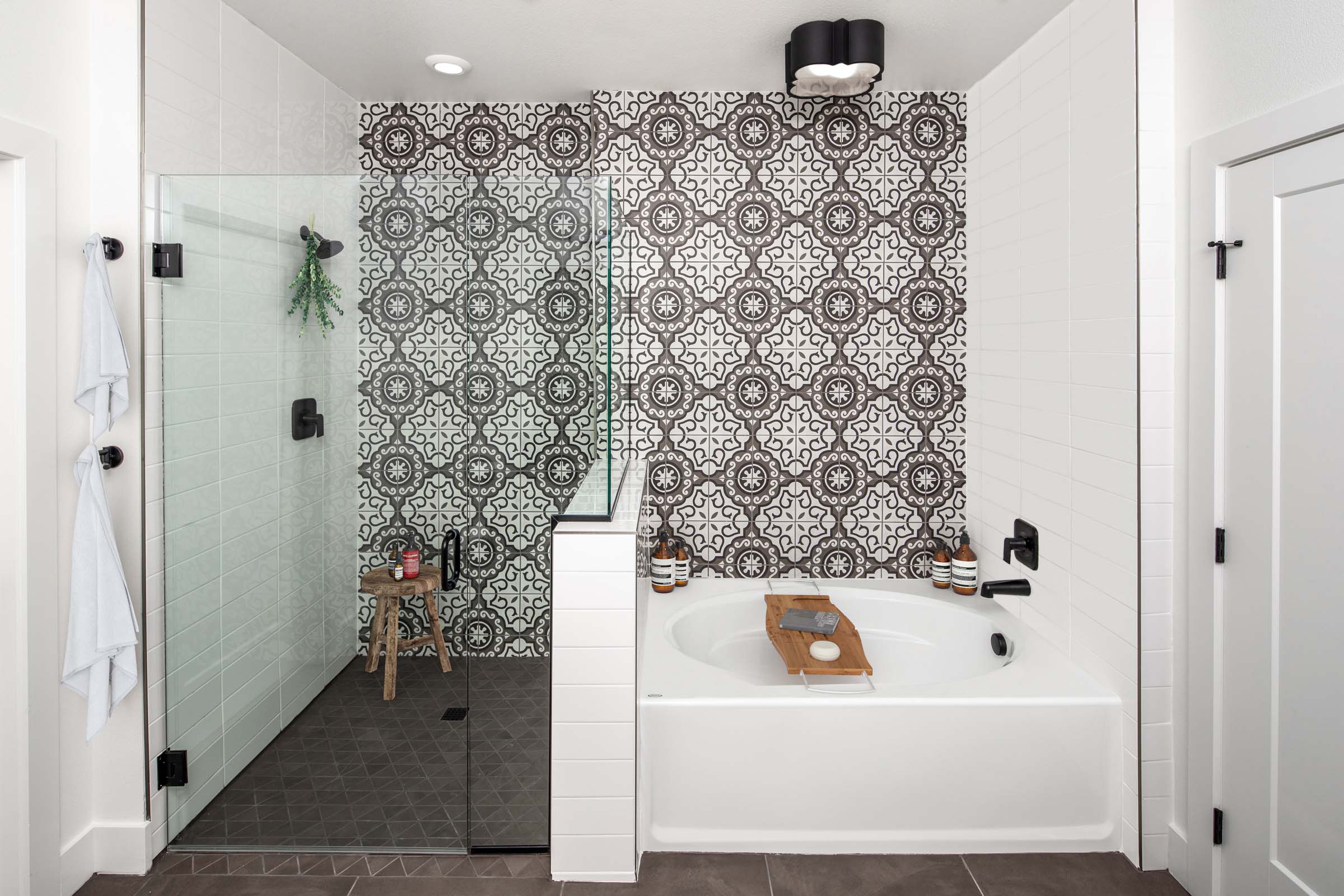 Camden Hillcrest apartments san diego ca five fixture main bathroom with italian inspired tiled accent wall and glass enclosed shower near soaking tub under designer lighting 