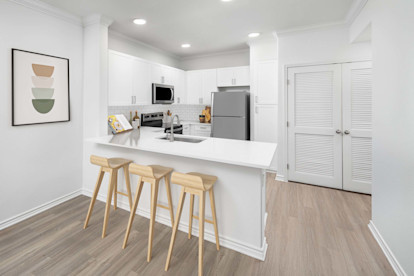 Kitchen with white quartz countertops and breakfast bar at Camden Northpointe Apartments in Tomball, Tx