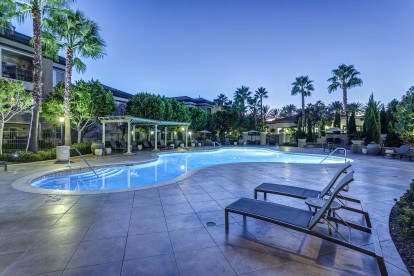 Resort style swimming pool with lounge chairs at dusk