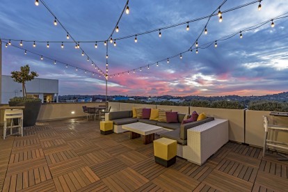 Skydeck lounge with seating areas and string lights at dusk overlooking los angeles