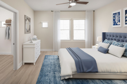 Bedroom with walk-in closet, ceiling fan, and wood-look flooring in a Magnolia home at Camden Woodmill Creek in Spring, TX