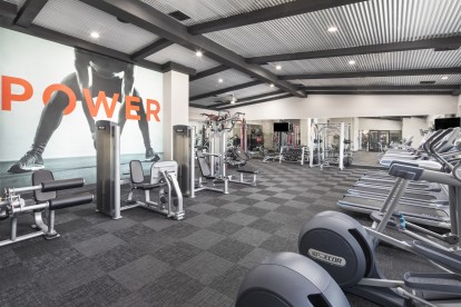 24-hour fitness center with cardio and strength training machines and dumbbells