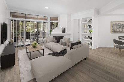 Living room with light gray wood-style floors, fireplace and large windows showing a spacious patio at Camden Gaines Ranch