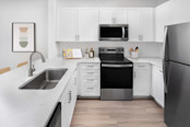 Kitchen with white quartz countertops, stainless steel appliances and white subway tile backsplash at Camden Northpointe Apartments in Tomball, Tx