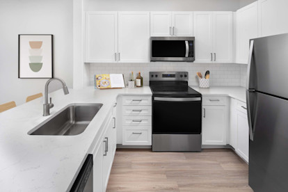 Kitchen with white quartz countertops, stainless steel appliances and white subway tile backsplash at Camden Northpointe Apartments in Tomball, Tx