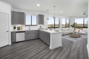 Camden Tempe West Apartments Tempe Arizona contemporary open concept windowed kitchen with white quartz countertops, stainless steel appliances, gray cabinetry, large pantry, and wood-like flooring throughout with floor to ceiling windows in nearby living room 