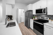 Renovated kitchen with white quartz countertops and white cabinets at Camden Addison apartments in Addison, TX