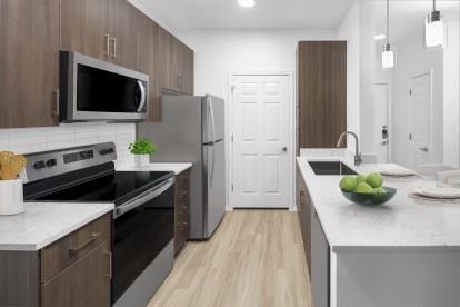 Camden San Marcos Apartments Scottsdale AZ spacious kitchen with woodlike flooring, stainless steel appliances, white quartz countertops, designer lighting, and brushed nickel fixtures