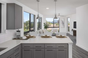 Camden Tempe West Apartments Tempe Arizona contemporary kitchen with modern gray shaker cabinets white quartz countertops and pendant lighting near open concept living room with ceiling fan and floor to ceiling windows 