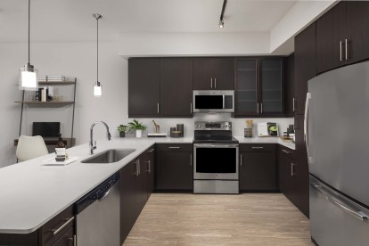 Kitchen with white quartz countertops and stainless steel appliances at Camden Rainey Street apartments in Austin, TX
