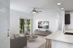 Living room with sliding glass doors to screened patio wood look flooring and ceiling fan