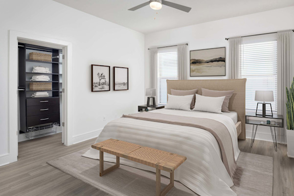 Townhome primary bedroom with custom closet shelves and drawers, wood-style floors, ceiling fan, and large windows at Camden Belmont apartments in Dallas, TX