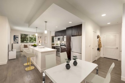 Open concept dining room near luxury kitchen with white quartz countertops, stainless steel appliances, and room for barstool seating