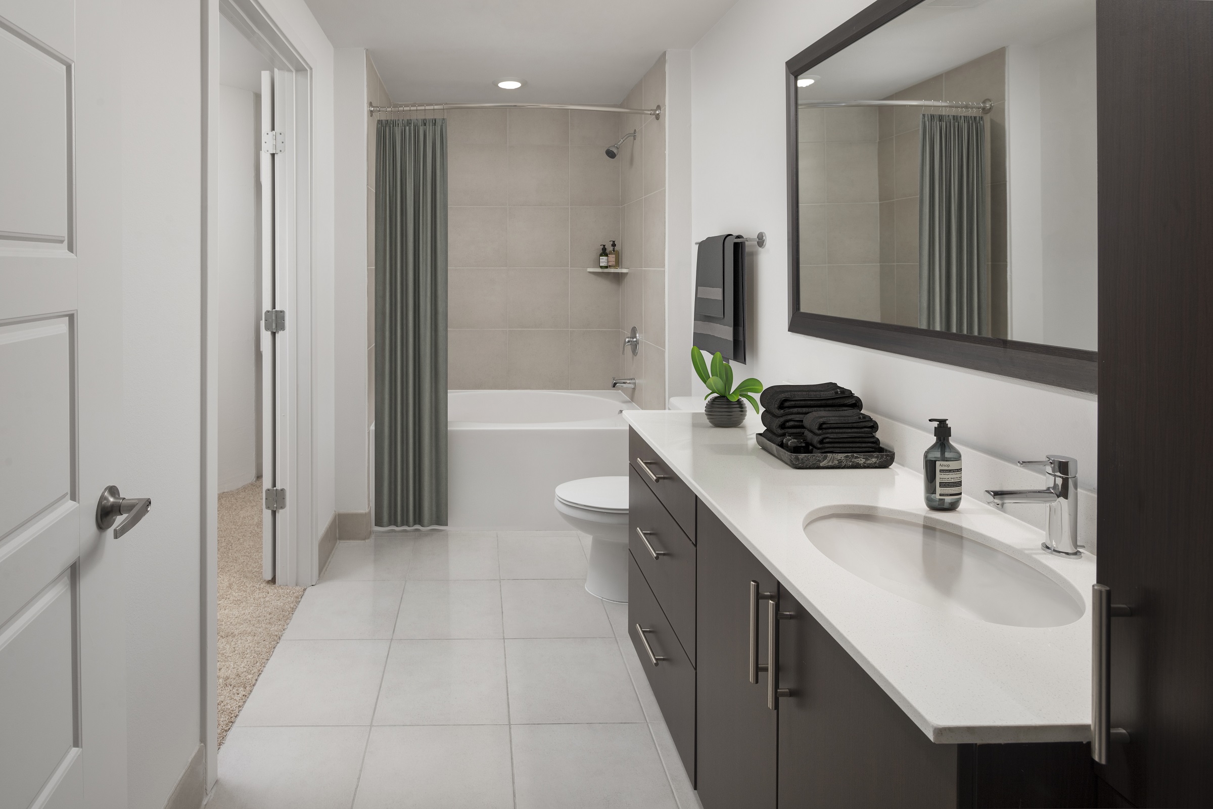 Bathroom with white quartz countertops and soaking bathtub at Camden Rainey Street