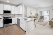 Modern kitchen with stainless steel appliances, white cabinetry, white quartz countertops and open-concept floor plan with sliding glass door to the private patio at Camden Spring Creek Apartments in Spring, Tx