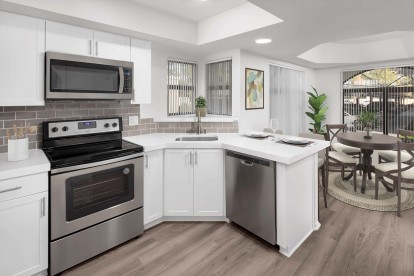 Open-concept windowed kitchen with stainless steel appliances and dining room