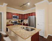 Kitchen with island and granite countertops and stainless steel appliances at Camden Brushy Creek apartments in Cedar Park, TX