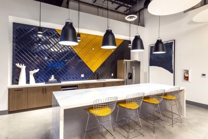 Resident lounge kitchen with barstool seating and white quartz countertops and blue subway tile backsplash