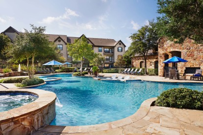 Resort style pool with water feature lounge seating and outdoor dining