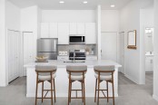 Kitchen with white quartz countertops, white cabinets and gray subway tile backsplash at Camden World Gateway apartments in Orlando, FL