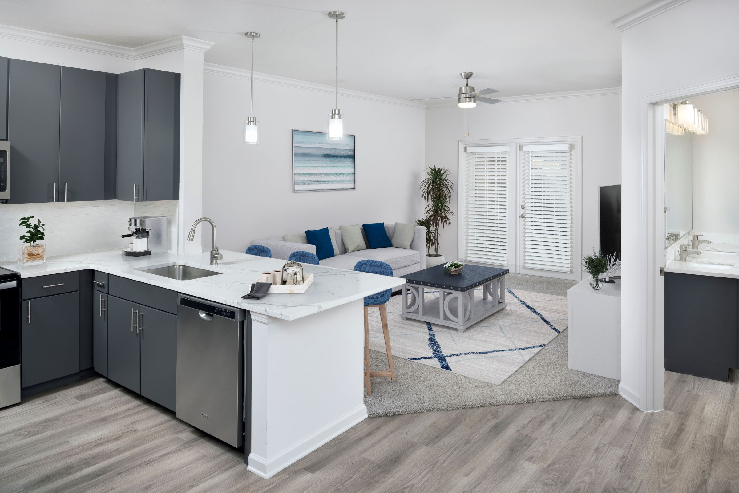 Open kitchen with stainless steel appliances, grey cabinetry, and quartz countertops. 