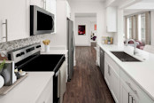 Spacious kitchen with stainless steel appliances, an electric cooktop, and a farmhouse sink at Camden Roosevelt apartments in Washington, DC.