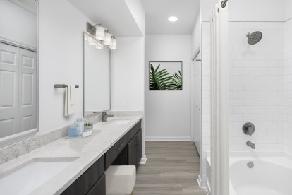 Modern finishes bathroom with double vanity, dark brown cabinetry, gray quartz countertops and white subway tile surround