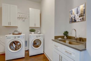 Camden Music Row Apartments Penthouse Utility Room with side-by-side front-loading washer and dryer, sink, cabinetry, and drying rack