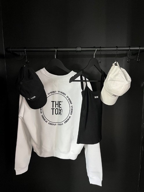 The Tox Technique Camden Music Row merchandise including a white sweatshirt with black The TOX logo and a couple of branded baseball caps