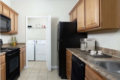 Kitchen with black appliances and tile flooring alongside laundry room with washer and dryer