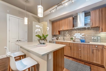 The Gallery kitchen with white quartz countertops, islands with bar seating, glass cooktops, and subway tile backsplash