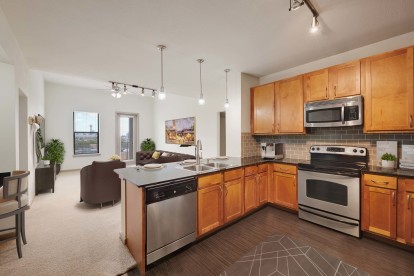 Kitchen with granite countertops wood look flooring and stainless steel appliances