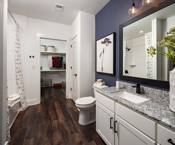 Bathroom with soaking bathtub, linen closet, and walk-in closet with wood-style flooring at Camden West Nashville apartments in Nashville, TN