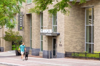 Resident walking dog by the front entry at Camden Music Row apartments in Nashville, TN